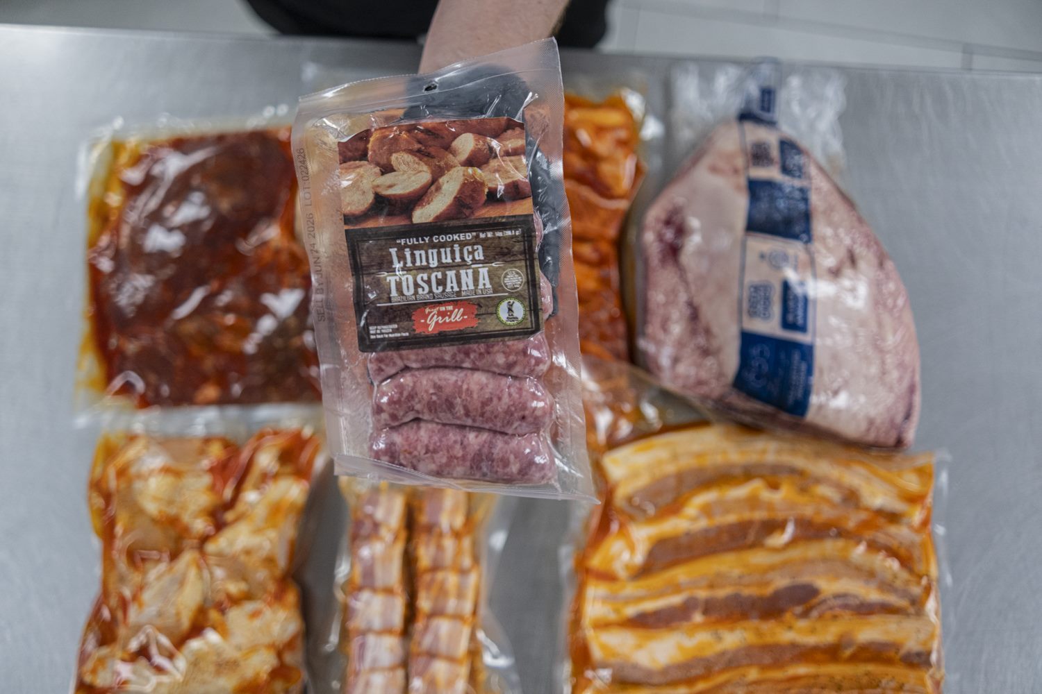 Vacuum-sealed marinated cuts, linguiça toscana and pork belly ready for the grill