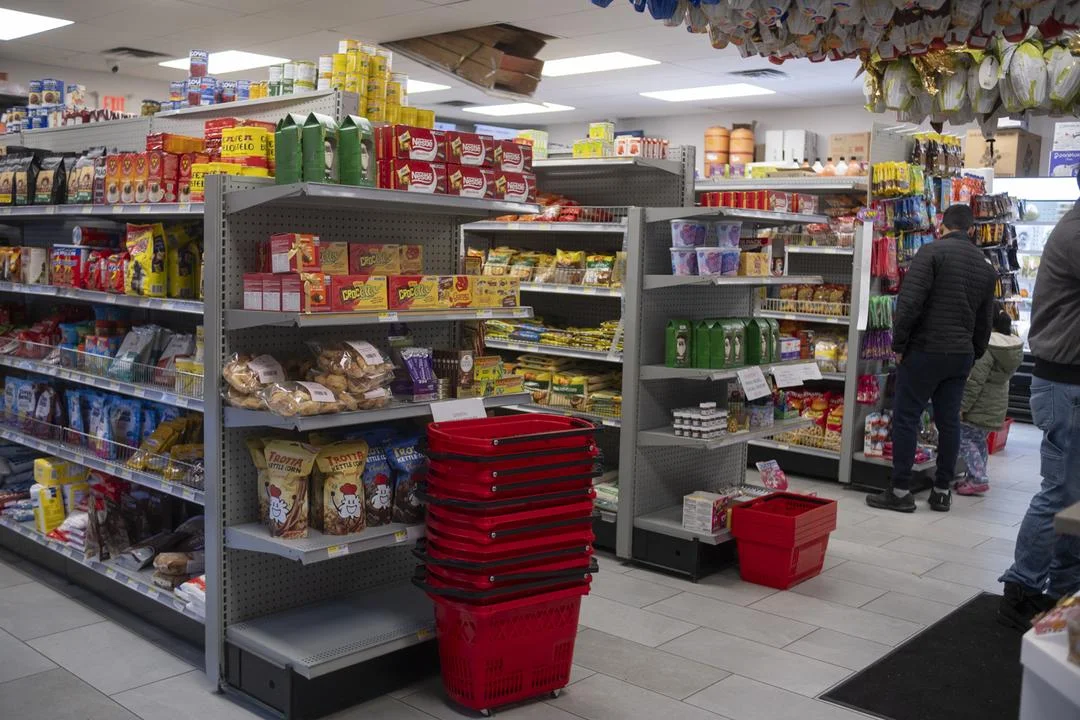 A Vitoria grocery aisle with stacked red shopping baskets, snack shelves and shoppers at the back