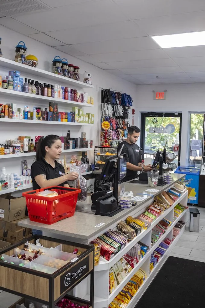 Two Vitoria staff at the front register, with a candy and snack display along the counter